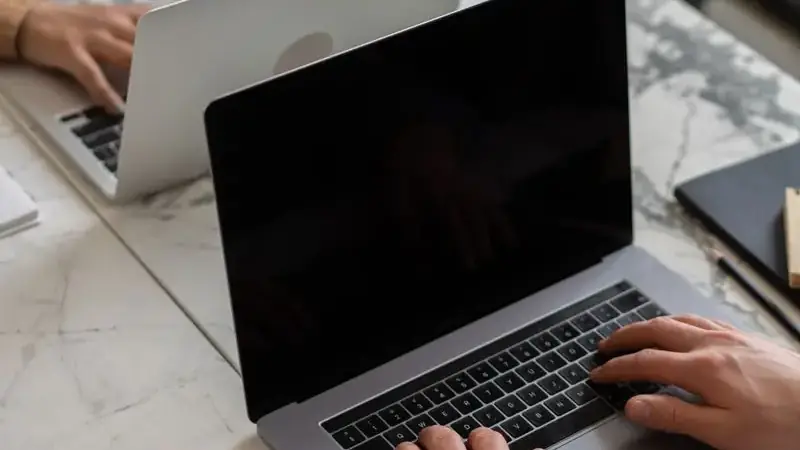 Person typing on a laptop during a laggy video call troubleshooting session