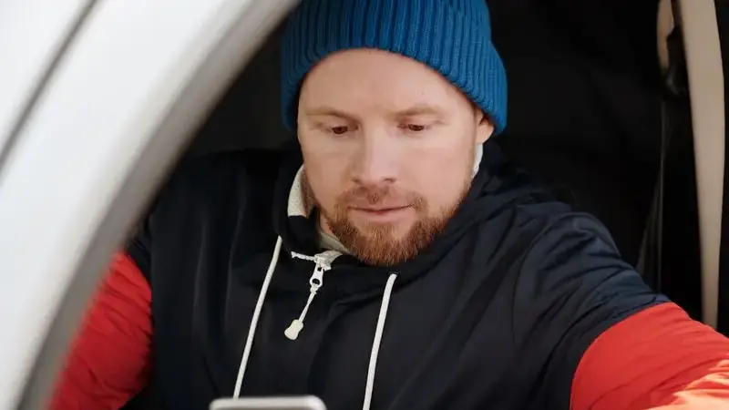 Man in a car using his phone, showing mobile Umingle usage on the go